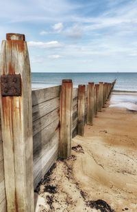 Wooden posts on beach against sky