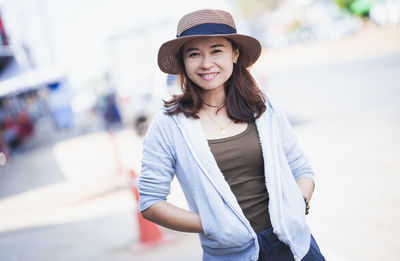 Portrait of smiling young woman wearing hat standing outdoors