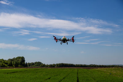 Airplane flying over field against sky