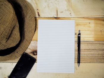 Directly above shot of sun hat with smart phone and paper on wooden table