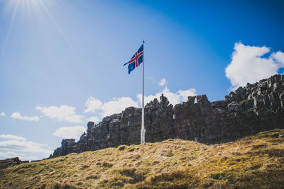 Low angle view of flag on mountain against sky