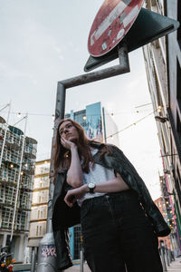 Low angle view of woman standing against building in city