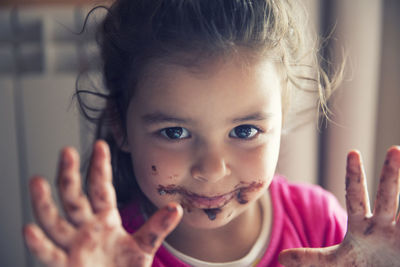 Close-up portrait of smiling girl with messy mouth and hands gesturing at home