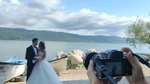 Friends photographing sea against sky