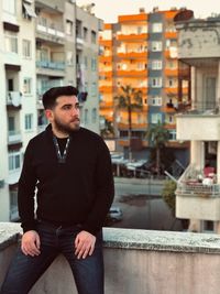 Portrait of young man standing against buildings