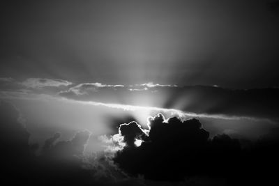 Low angle view of sunlight streaming through clouds