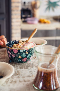 Tasty smoothie bowl with granola and blueberries served on table with soaked flax seeds during breakfast time in light kitchen