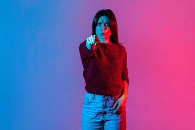 Young woman looking away against blue background