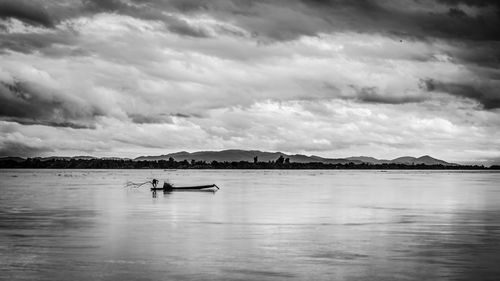 Man on boat in lake against sky