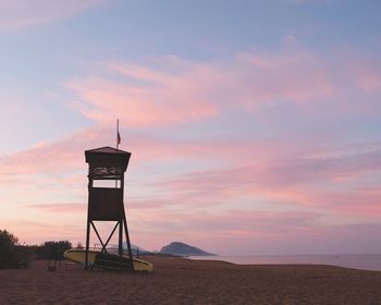 Lifeguard hut on beach against sky during sunset