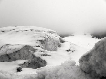 Snow covered rocks against snowcapped mountain