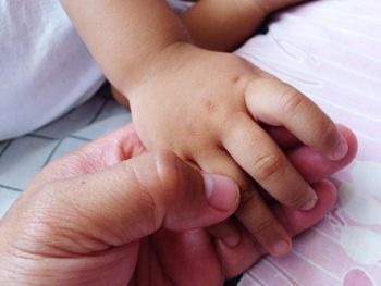 Cropped image of family holding hands on bed