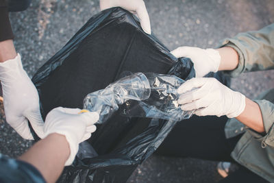 High angle view cropped hands collecting waste on road