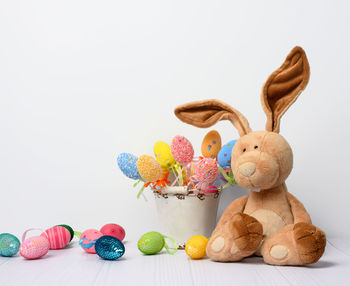 Teddy bunny sitting on a white background and decorative colorful easter eggs, close up