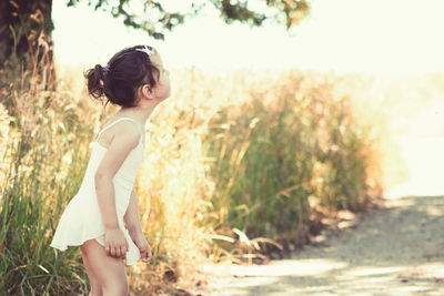 Side view of young woman standing against trees