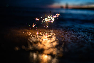 Close-up of sparklers on field at night