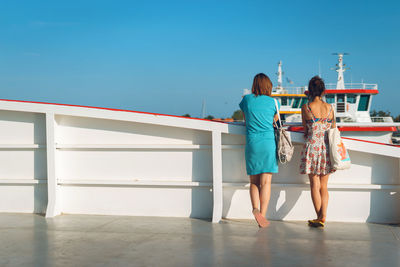 Rear view of women standing against clear sky