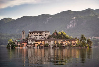 Buildings by river against sky