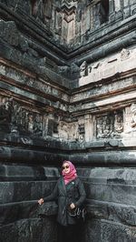 Full length of woman standing against wall and building