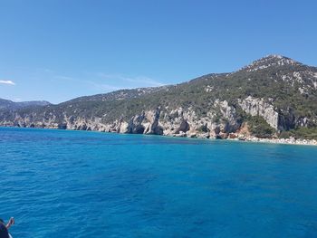 Scenic view of swimming pool by sea against clear blue sky