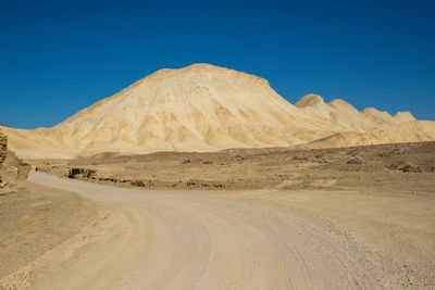 Scenic view of desert against clear blue sky