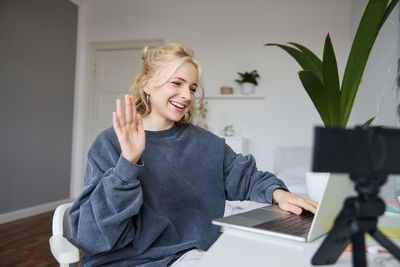 Young woman using mobile phone while sitting on table