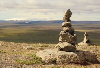 Stack of stones on landscape against sky