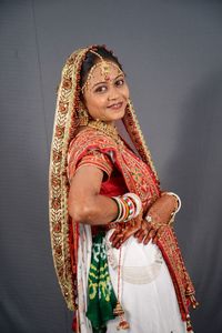 Portrait of smiling young bride standing against wall