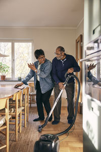 Senior couple having fun while cleaning home