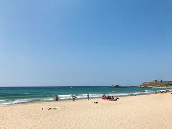 Scenic view of beach against clear blue sky