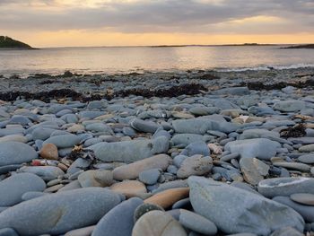 Rocks on beach against sky during sunset