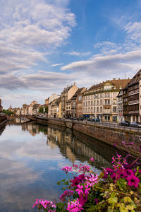 Scenic view of river by buildings against sky