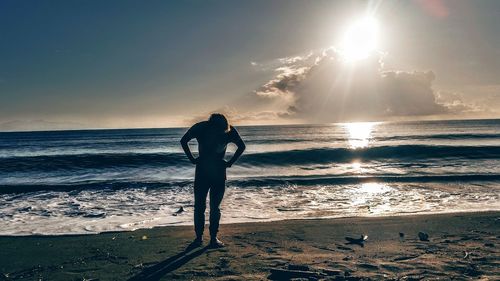 Silhouette man standing at beach against sky