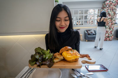 Young woman looking at camera while sitting on table at home