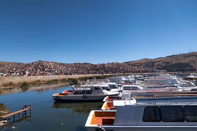 Boats moored on river against clear blue sky