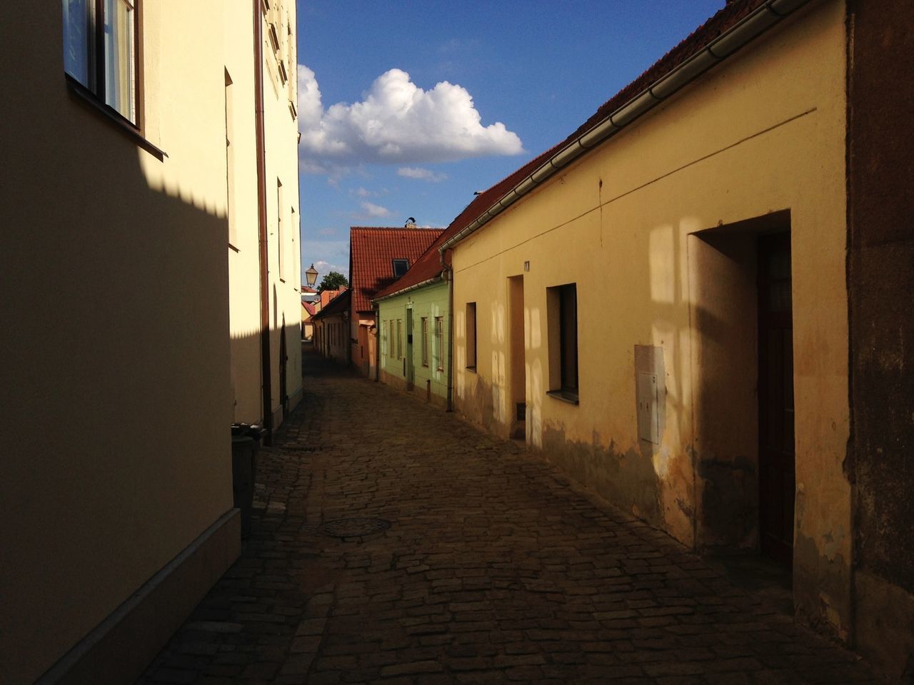 architecture, built structure, building exterior, the way forward, narrow, sky, residential structure, diminishing perspective, building, residential building, house, cobblestone, walkway, alley, empty, long, vanishing point, street, sunlight, day