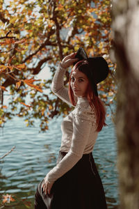 Young woman wearing hat standing against plants