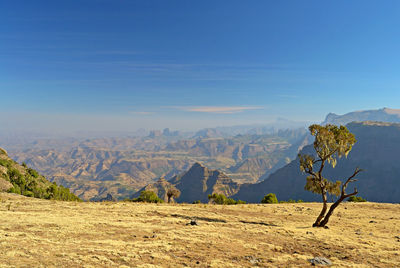 Scenic view of landscape and mountains against blue sky