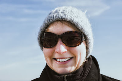 Portrait of smiling woman wearing sunglasses against sky