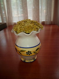 Close-up of vase on table against window at home