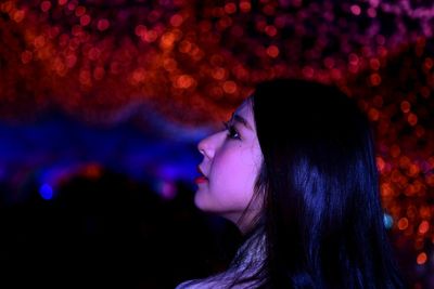 Close-up portrait of woman with illuminated hair at night