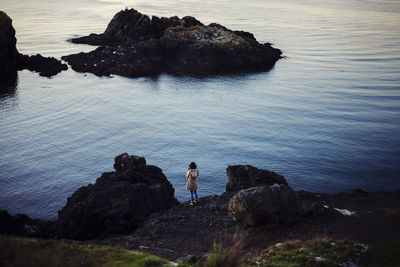 Woman sitting on rock by sea