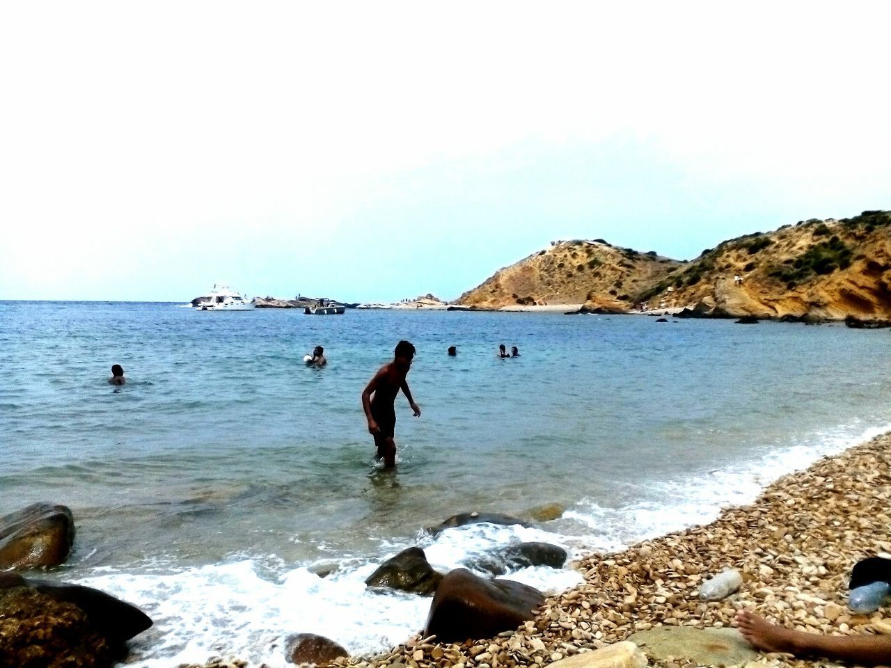 sea, water, leisure activity, lifestyles, beach, rock - object, vacations, shore, men, clear sky, enjoyment, scenics, beauty in nature, horizon over water, nature, rock formation, wave, person, sky