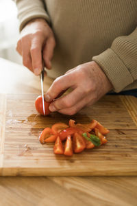 Midsection of man cutting meat on table