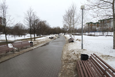 Snow covered street by canal against sky