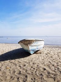 Boat moored on beach against sky