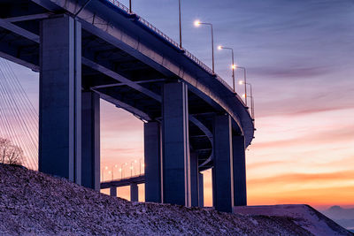 Low angle view of illuminated bridge against sky at sunset