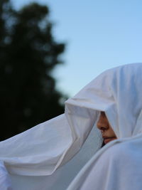 Midsection of woman covering face on bed