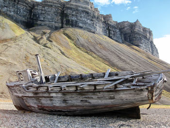 Old abandoned boat on beach against sky