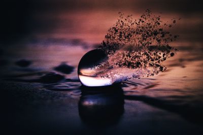 Close-up of water on table against sea during sunset